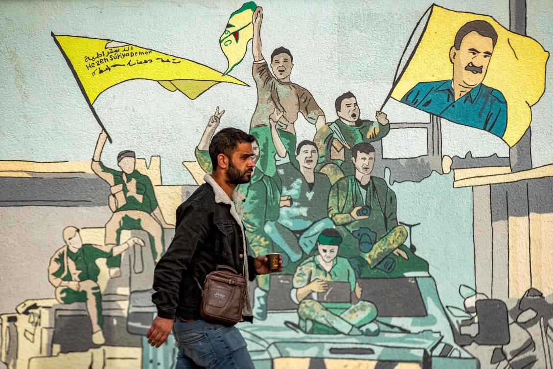 A man walks past a mural depicting supporters of the Syrian Democratic Forces in Syria’s northeastern city of Qamishli on December 16, 2024. (AFP)