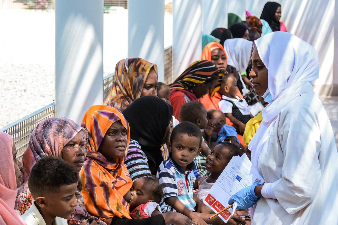 A nurse registers women with children waiting in the shade to receive medical care outside the Italian Paediatric Hospital in Port Sudan on October 8, 2024. (AFP)