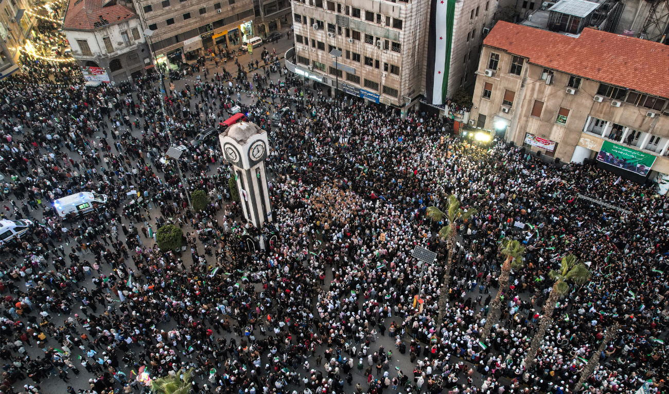 This aerial view shows people celebrating the ouster of Syria's president Bashar Assad, around the New Clock Tower along Quwatli Street in the centre of Homs on December 18, 2024. (AFP/File)