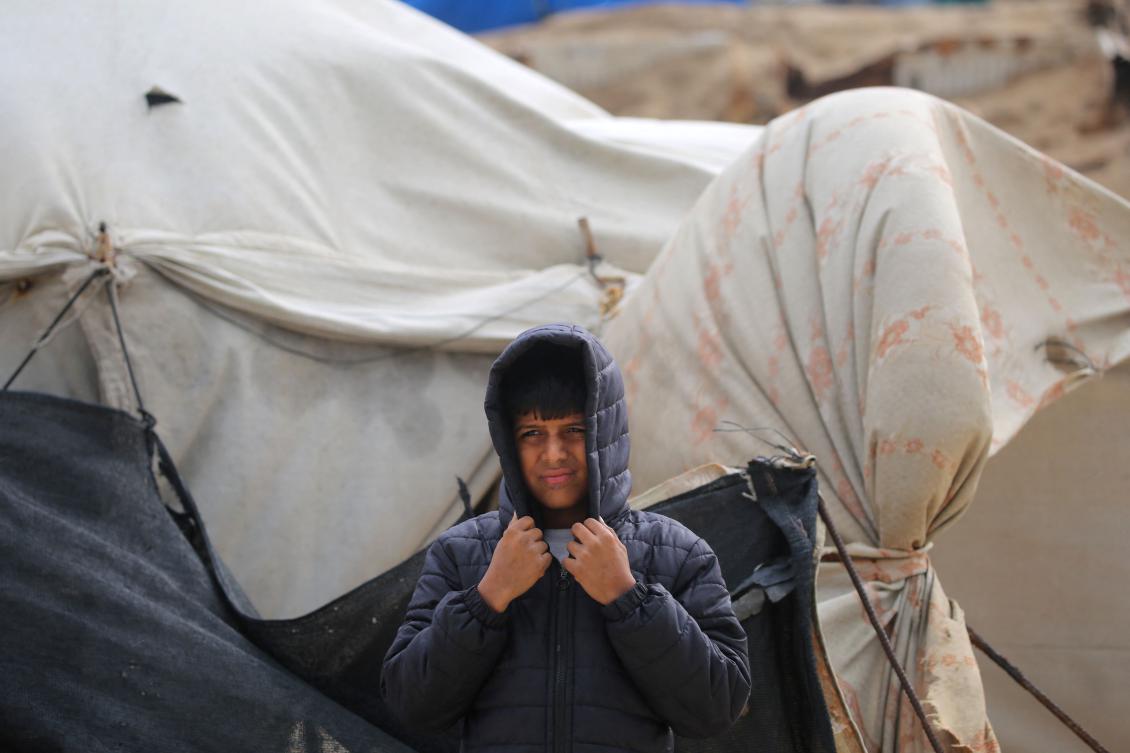 A Palestinian boy covers his head as the wind blows at a camp for the internally displaced on the beach near the Nuseirat refugee in the central Gaza Strip on December 20, 2024, amid the continuing war between Israel and Hamas. (AFP)