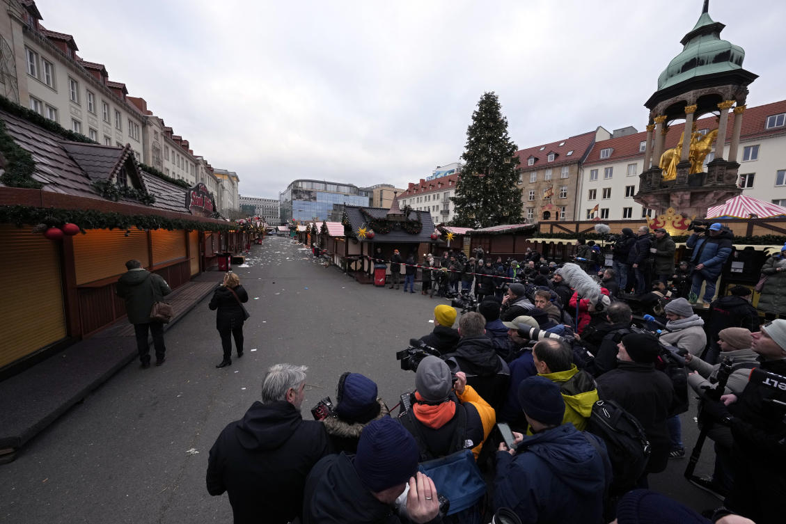 Journalists wait for the arrival of the Chancellor of Germany Olaf Scholz at Christmas Market, where a car drove into a crowd on Friday evening, in Magdeburg, Germany, Saturday, Dec. 21, 2024. (AP Photo/Michael Probst)