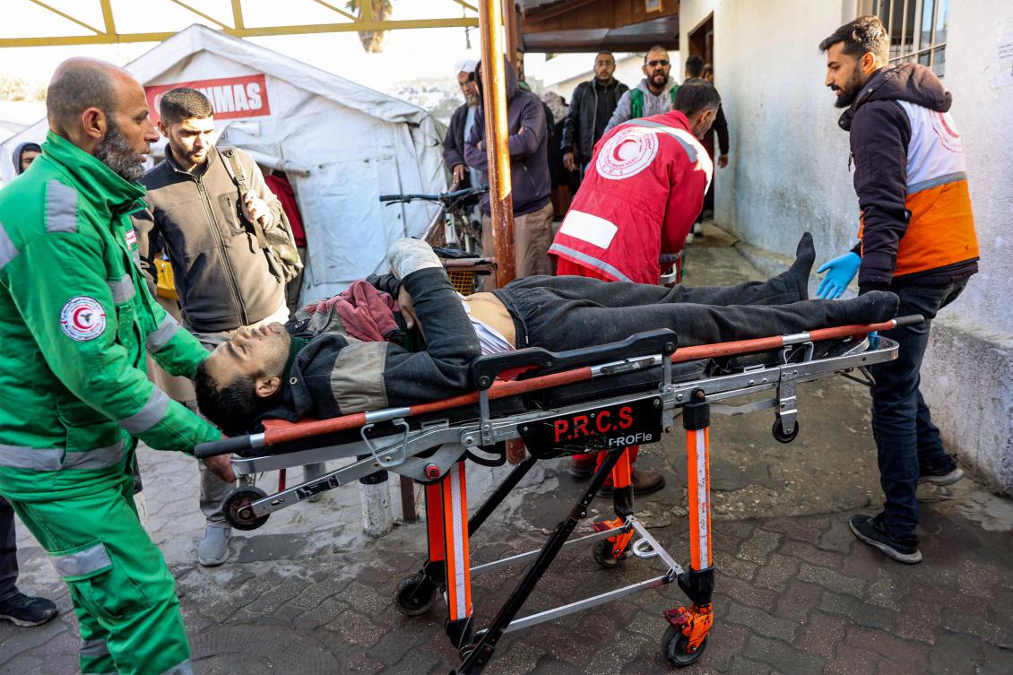 Palestinian Red Crescent paramedics transport on a gurney a person who was injured in a reported strike on a Palestinian civilian vehicle by Israeli forces, after arriving for medical care at the Ahli Arab Hospital in Gaza City on December 22, 2024 amid the ongoing war in the Palestinian territory between Israel and Hamas. (AFP)