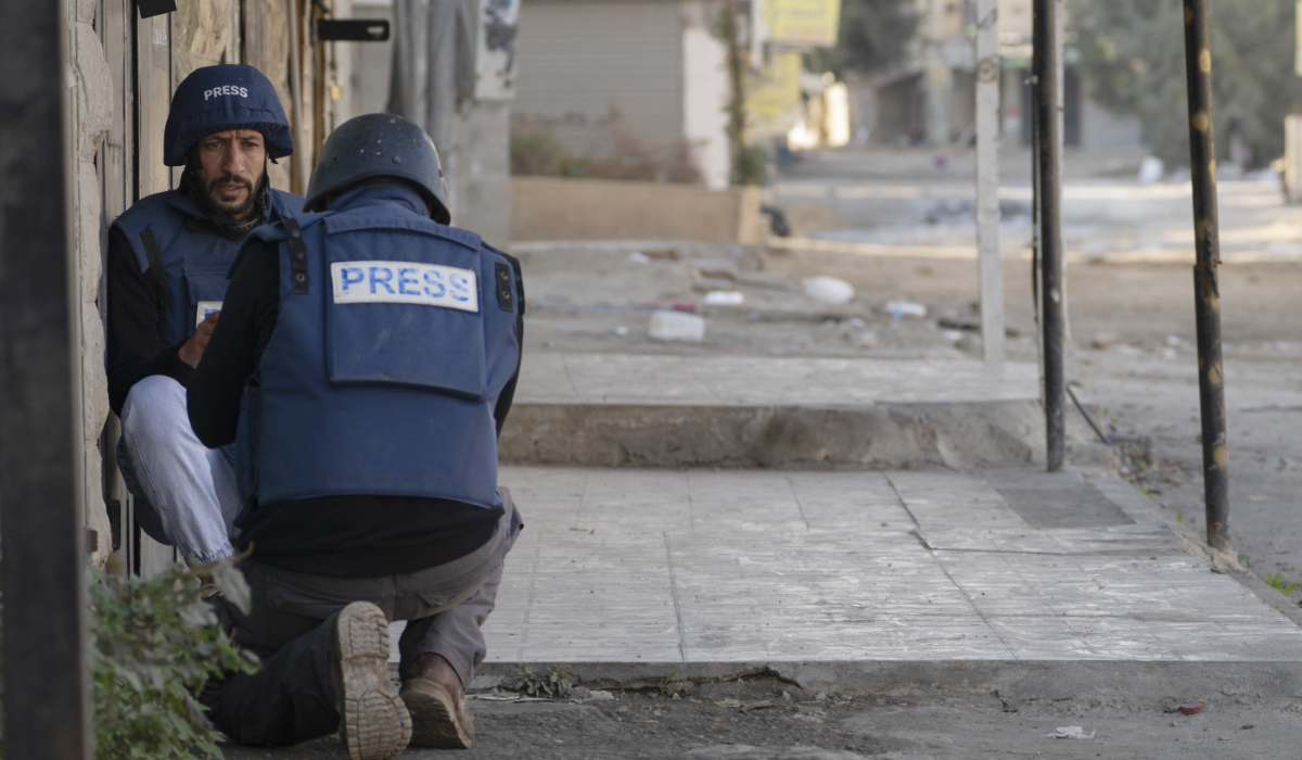 Journalists take cover from gunfire as Palestinian security forces mount a major raid against militants in the Jenin refugee camp in the Israeli-occupied West Bank, Monday, Dec. 23, 2024. (AP)