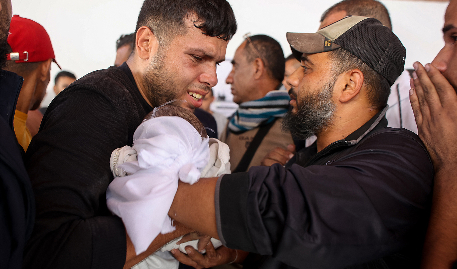 Men carry the body of a baby at Al-Ahli Arab hospital, also known as the Baptist hospital in Gaza City, after a house was hit by Israeli bombardment south of the city, on November 12, 2024. (AFP/File)