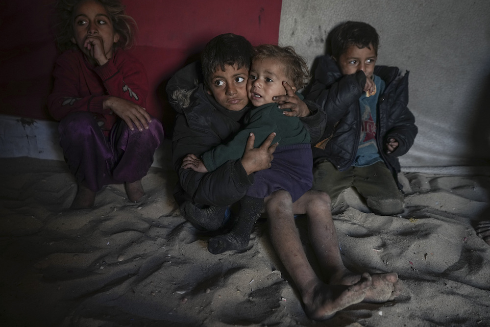 Palestinian Tamim Marouf, 6, sits inside his family's tent alongside his sister Hala, 10, and his brother Malek, 4, at a camp for internally displaced Palestinians on the beachfront in Deir Al-Balah, central Gaza Strip, Friday, Dec. 27, 2024. (AP)
