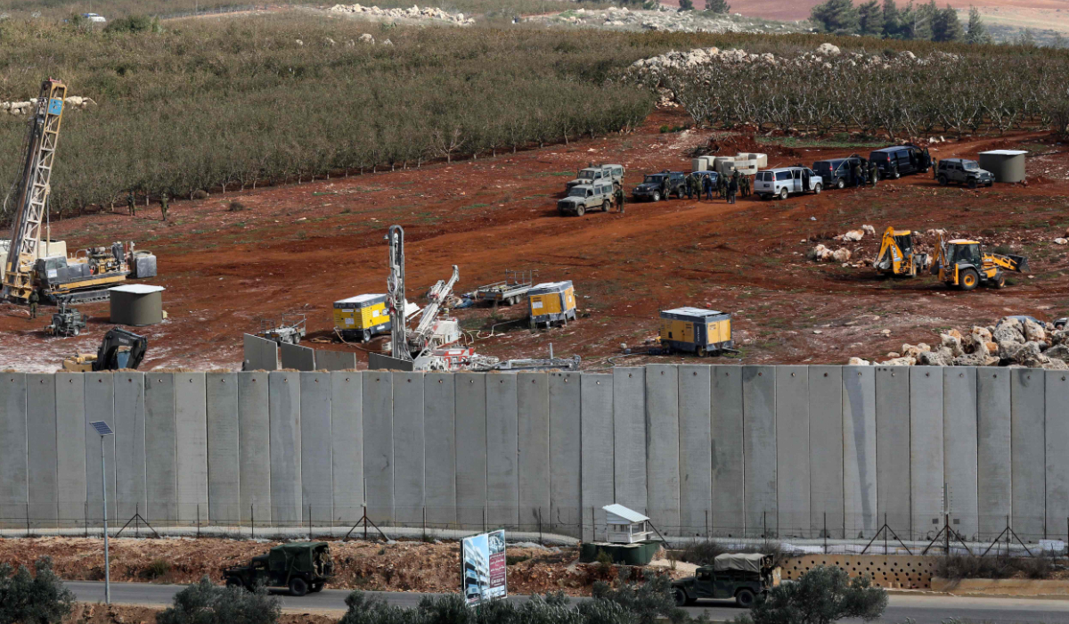 A picture taken on December 5, 2018 in the southern Lebanese village of Kfar Kila near the border with Israel shows Israeli machinery (top) operating next to the concrete border wall. (AFP file photo)