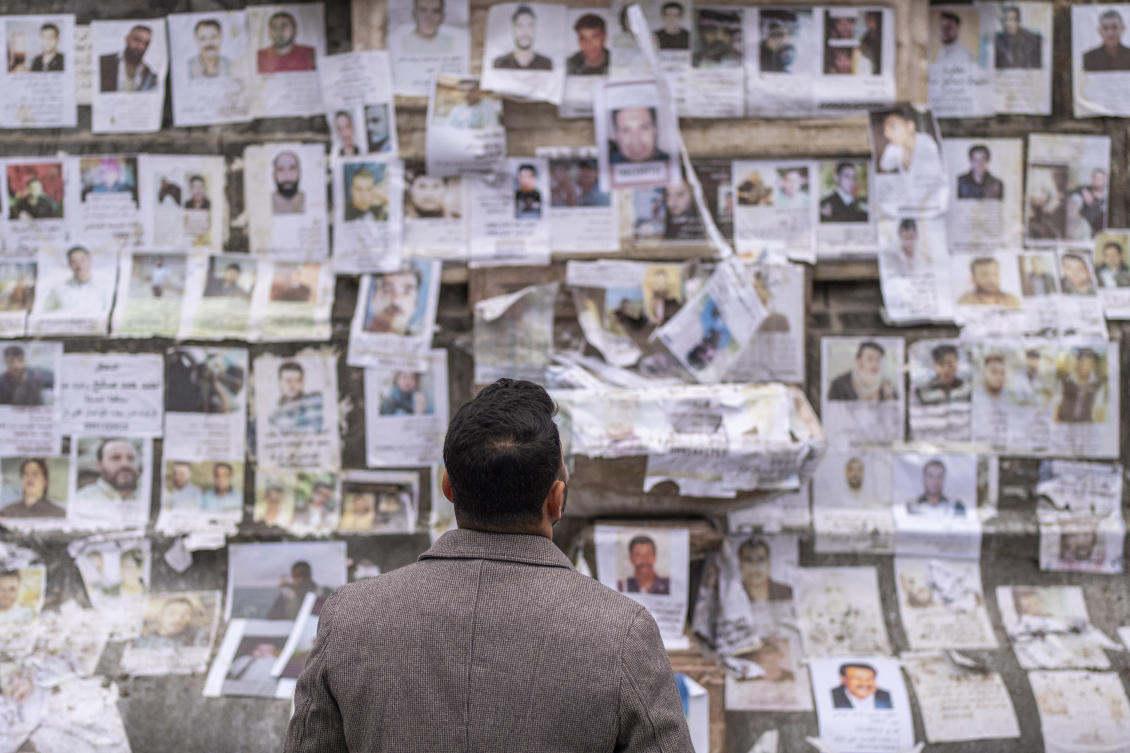 A man inspects portraits of missing people whose families say they were taken by the Assad regime are plastered across a monument in Damascus on Dec. 28, 2024. (AP)
