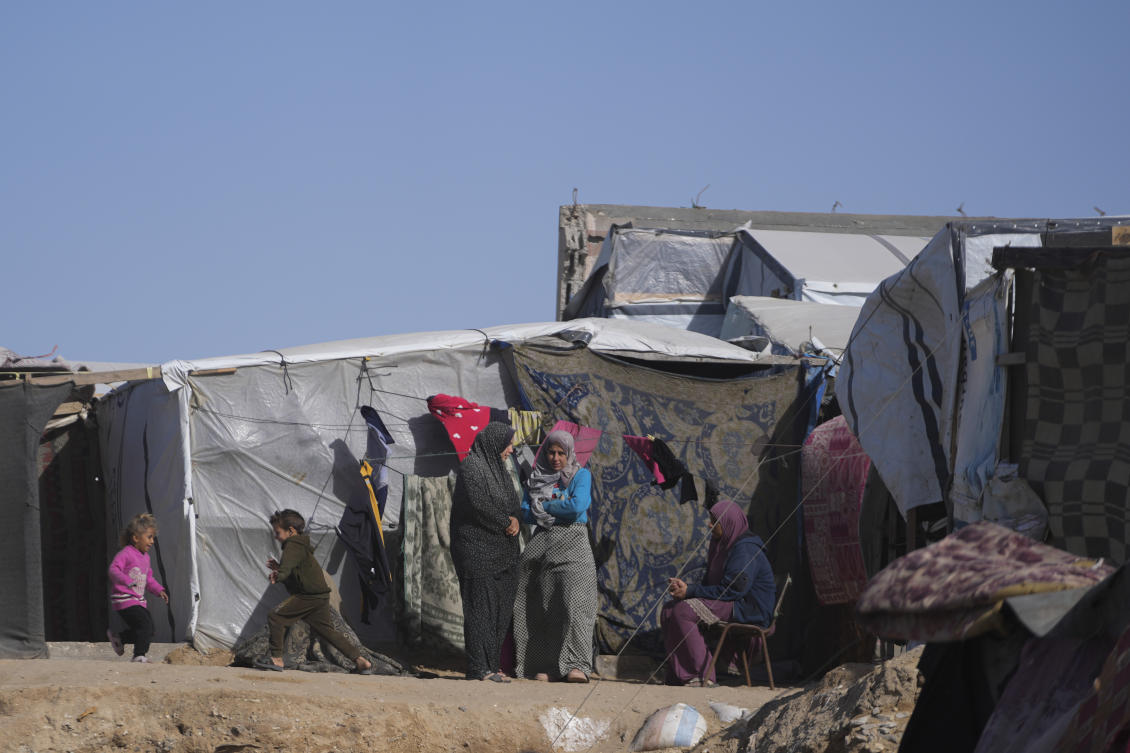 Palestinian families sit outside of tents made locally from pieces of cloth and nylon, in a camp for internally displaced Palestinians at the beachfront in Deir Al-Balah, central Gaza Strip, Friday, Dec. 27, 2024. (AP Photo/Abdel Kareem Hana)
