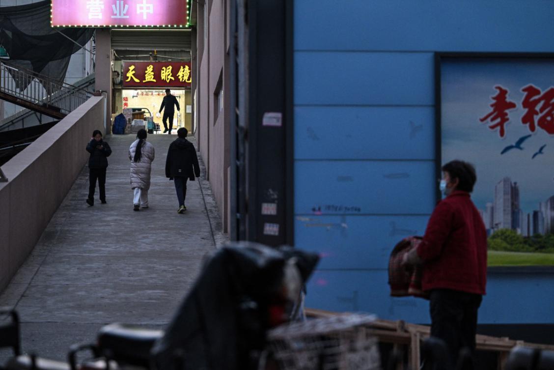 People walk past to the closed Huanan Seafood Wholesale Market in Wuhan in China’s central Hubei province on December 20, 2024. (AFP)