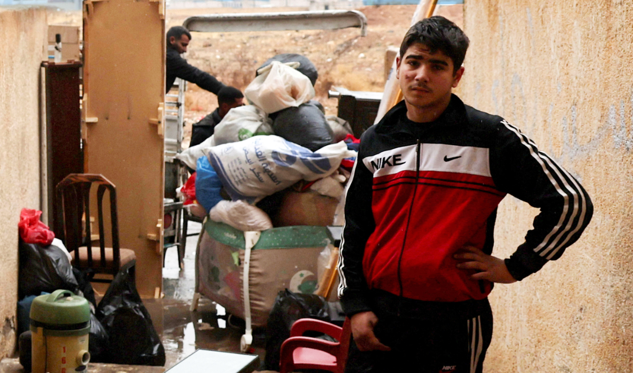 A young man near Damascus waits for workers to move his family’s belongings following evacuation orders. (Reuters)