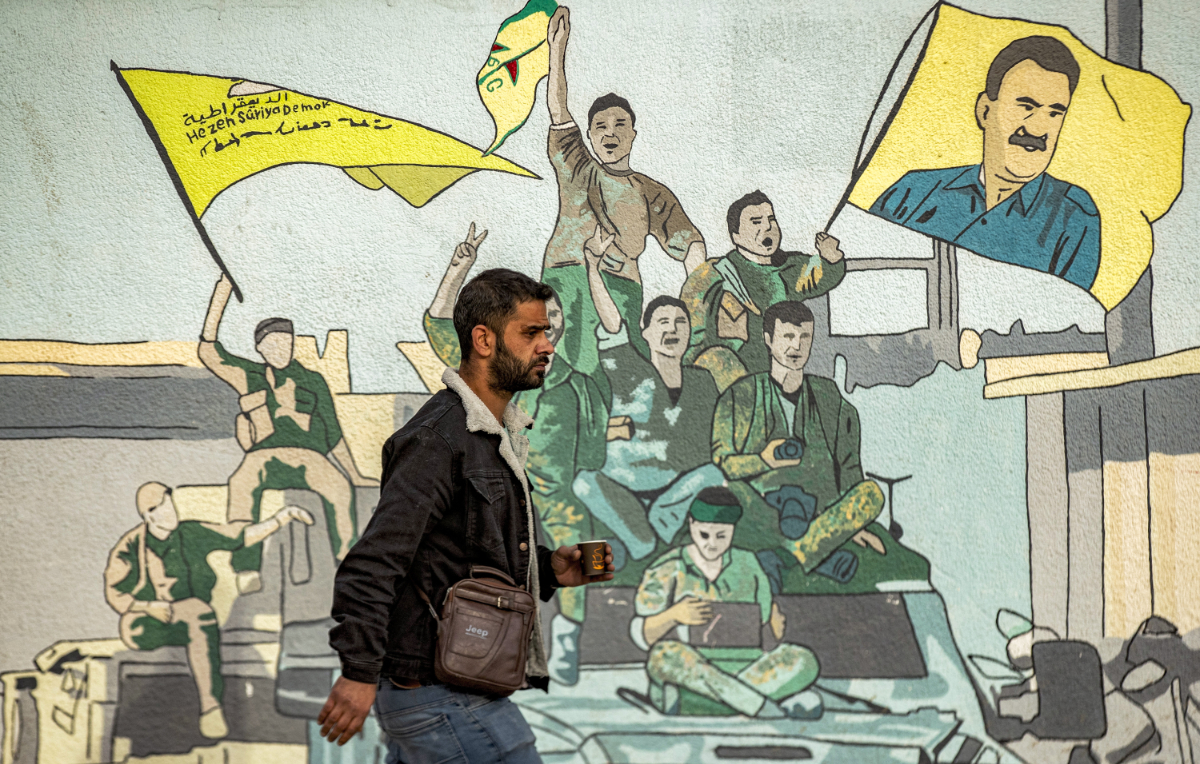 A man walks past a mural depicting supporters of the Syrian Democratic Forces (SDF), one of them raising a flag showing the face of Abdullah Ocalan -- founding member of the militant Kurdistan Workers' Party (PKK) outlawed by Turkey, in Syria's northeastern city of Qamishli on December 16, 2024. (AFP)