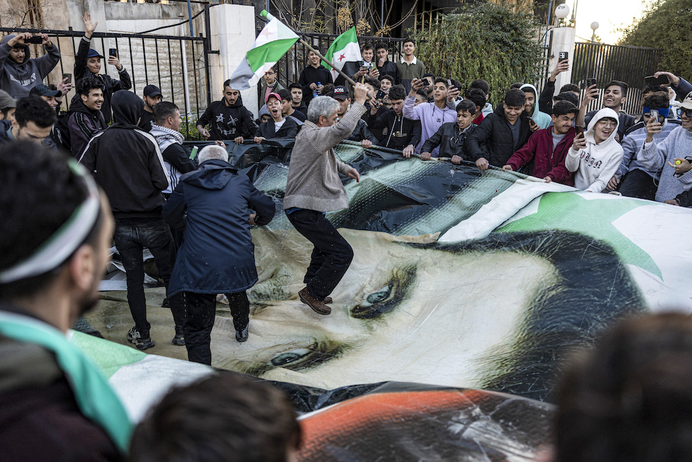 People stomp on a banner depicting the face of Syria’s ousted president Bashar Assad during a rally in Damascus. (AFP)