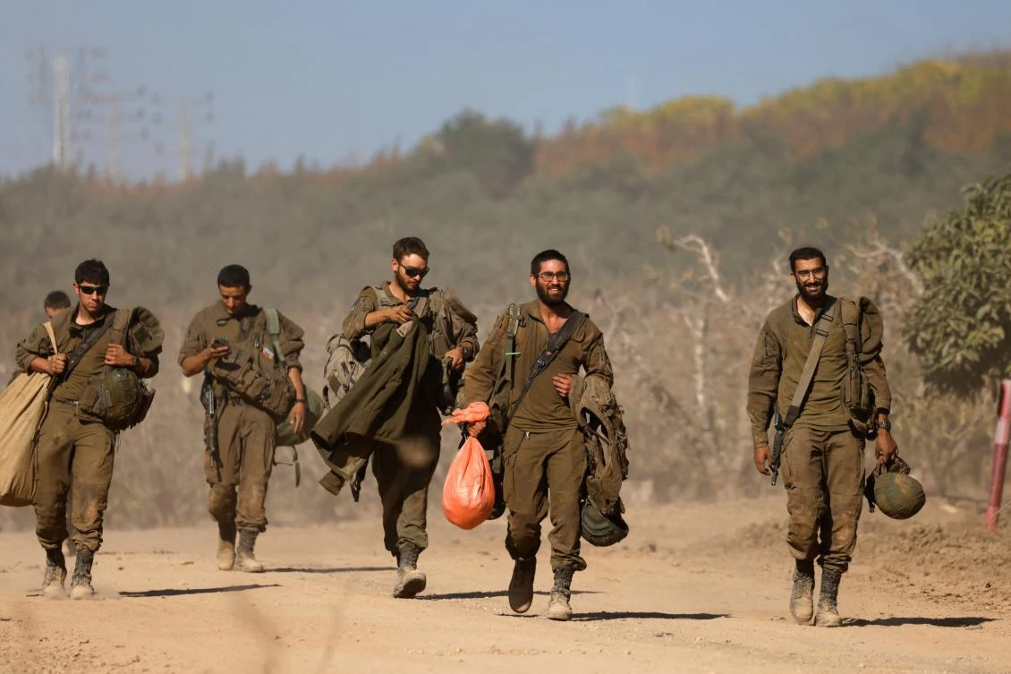 Israeli soldiers carry their belongings as they prepare for a military leave near their positions on the border with Lebanon on Dec. 3, 2024. (AFP)