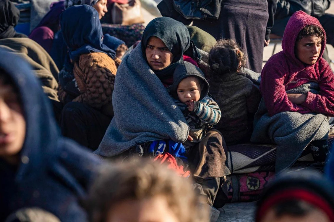 A Syrian Kurdish woman and her child waits with others upon their arrival in Tabqa, on the western outskirts of Raqa, after fleeing fighting north of Aleppo. (AFP)