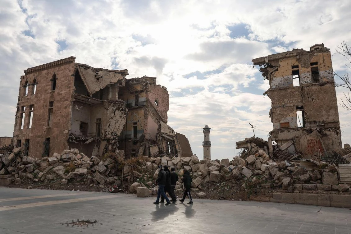 Syrians walk past one of Aleppo’s destroyed structures near the northern city’s historic citadel on Dec. 5, 2024, the day militant forces, led by Hayat Tahrir Al-Sham (HTS), captured the central city of Hama, nearly a week after seizing Aleppo. (AFP)