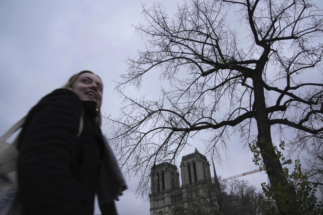 A woman walks in front of Notre-Dame de Paris cathedral ahead of Saturday’s reopening ceremony, Dec. 5, 2024 in Paris. (AP)