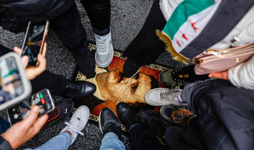 Demonstrators trample a carpet with a design showing President Bashar Al-Assad during a protest. (AFP)