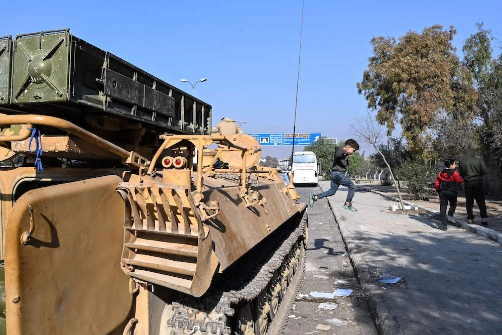 Above, a child jumps from a military vehicle abandoned by the Syrian army in Damascus airport highway on Dec. 9, 2024. (AFP)