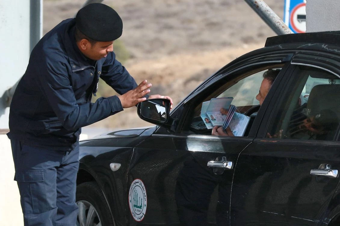 A Jordanian police officer checks the documents of Syrians returning to their counrty through the Jaber border crossing on December 8, 2024, following the fall of the Syrian capital Damascus. (AFP)