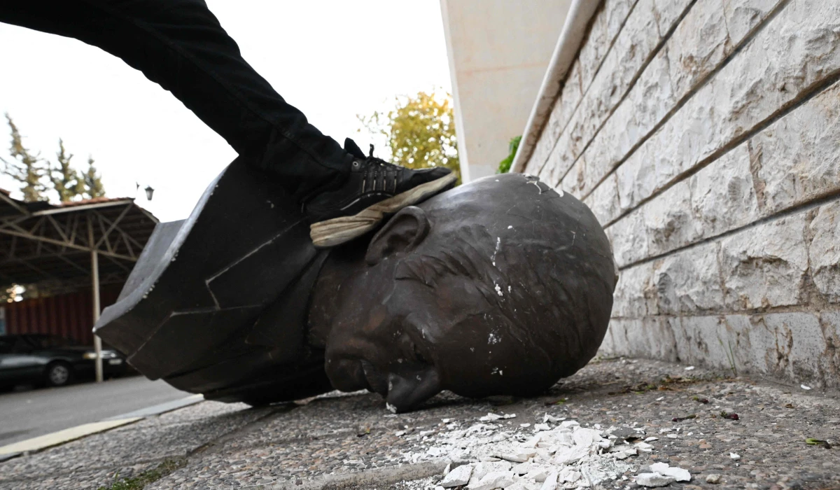 An anti-government fighter steps on the head of a statue of late Syrian president Hafez al-Assad that was brought down outside the Defence Ministry's military security headquarters in the Damascus district of Kafr Sousa on December 9, 2024. (AFP)