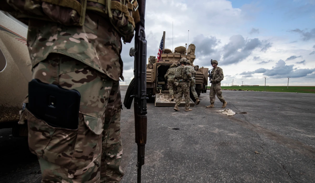 A member of the Syrian Democratic Forces (SDF) (L) and US soldiers are pictured near an armoured military vehicles are pictured on the outskirts of Rumaylan in Syria's northeastern Hasakeh province, bordering Turkey, on March 27, 2023. (AFP)
