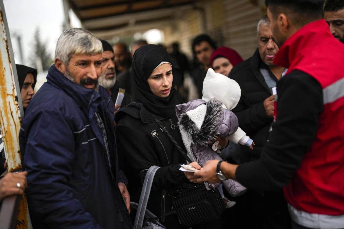 An officer checks the papers of a Syrian woman before she crosses into Syria from Turkiye, at the Oncupinar border gate in southern Turkiye on Dec. 11, 2024. (AP)