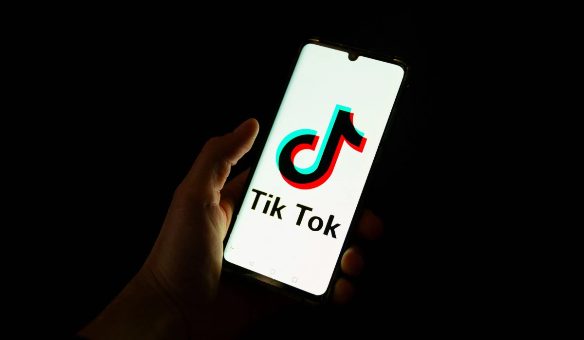 This photograph taken on April 19, 2024 shows a man holding a smartphone displaying the logo of Chinese social media platform Tiktok in an office in Paris. (AFP)