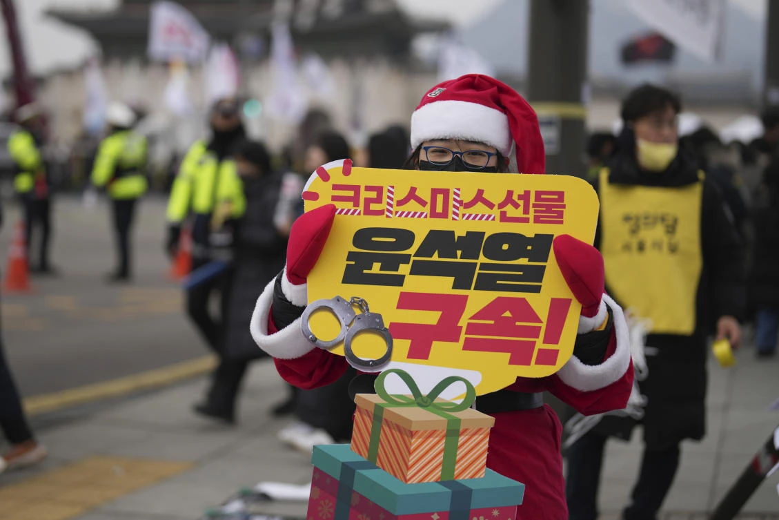 A protester wearing a Santa Claus costume holds a sign reading ‘Arrest Yoon Seok Yeol’ during a rally in Seoul on Dec. 21, 2024. (AP)