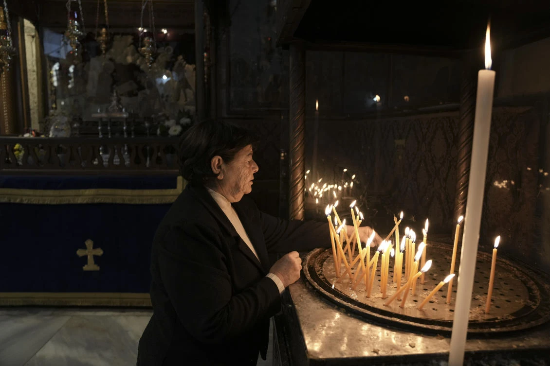 A worshipper lights a candle in the Church of the Nativity, where Christians believe Jesus Christ was born, ahead of Christmas in the West Bank city of Bethlehem, Tuesday, Dec. 17, 2024. (AP)