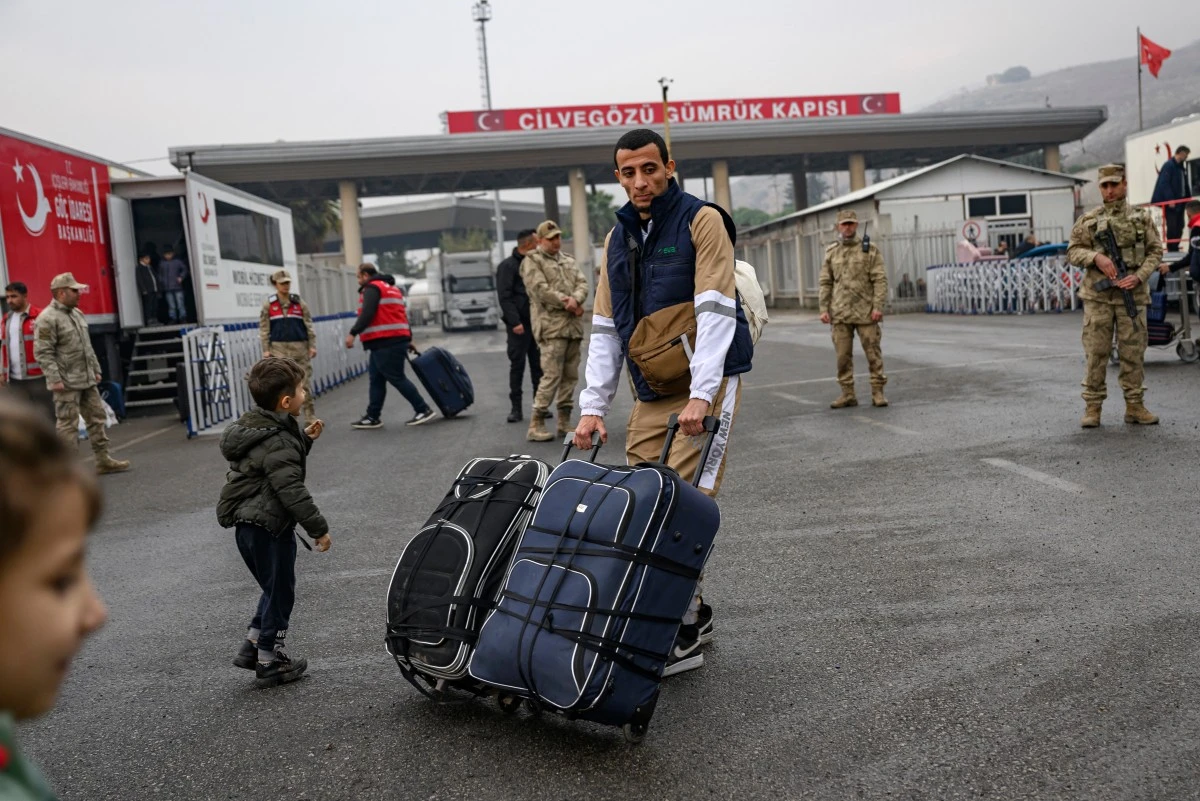 A Syrian living in Turkey pushes his suitcases at the Cilvegozu border crossing gate in Reyhanli on December 12, 2024, on the way back to his country following the oust of Syrian president. (AFP)