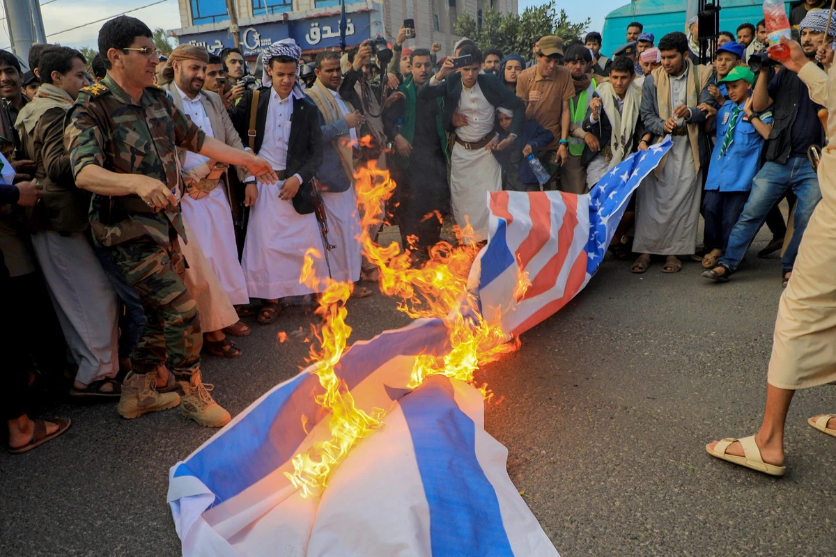 People set a US and an Israeli flag on fire during a march to show solidarity with the Palestinians of the Gaza Strip on October 18, 2023, in the Houthi-controlled Yemeni capital Sanaa. (File/AFP)