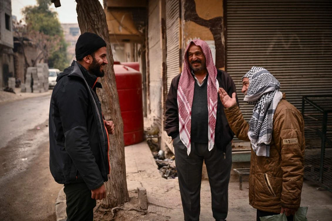 Syrian AFP photographer Sameer Al-Doumy talks with people from his old neighborhood in the city of Douma near Damascus on December 22, 2024. (AFP)