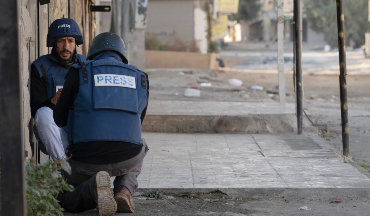 Journalists take cover from gunfire as Palestinian security forces mount a major raid against militants in the Jenin refugee camp in the Israeli-occupied West Bank, Monday, Dec. 23, 2024. (AP)
