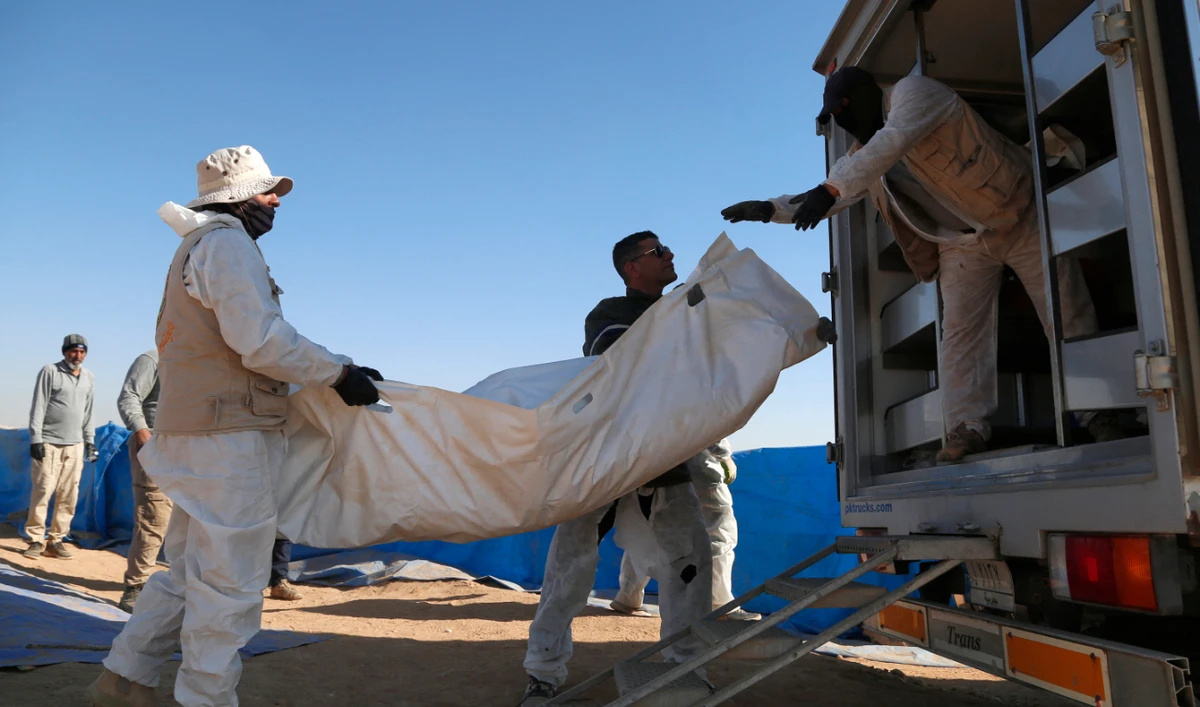 Forensic experts load human remains exhumed from a mass grave onto a truck in Tal Al-Shaikhia in the Muthanna province in southern Iraq on December 25, 2024. (AFP)