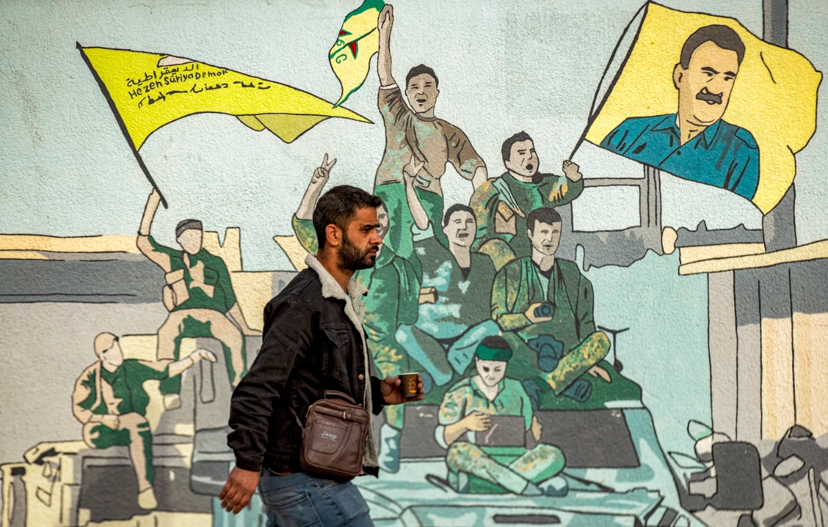 A man walks past a mural depicting supporters of the Syrian Democratic Forces (SDF), one of them raising a flag showing the face of Abdullah Ocalan -- founding member of the militant Kurdistan Workers' Party (PKK) outlawed by Turkey, in Syria's northeastern city of Qamishli on December 16, 2024. (AFP)