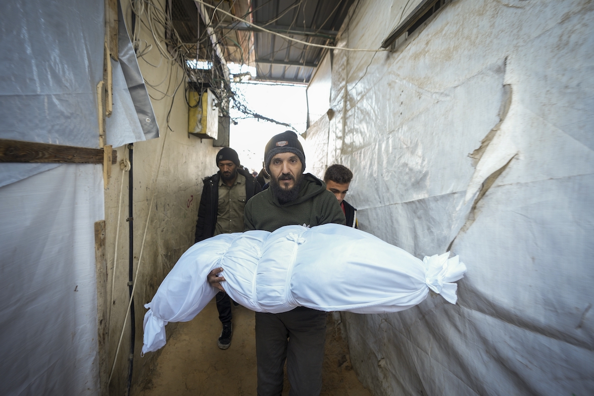 The body of a victim of an Israeli army strike on a house in the Bureij refugee camp is carried for the funeral at the Al-Aqsa Martyrs Hospital in the central Gaza Strip on Jan. 1. (AP)