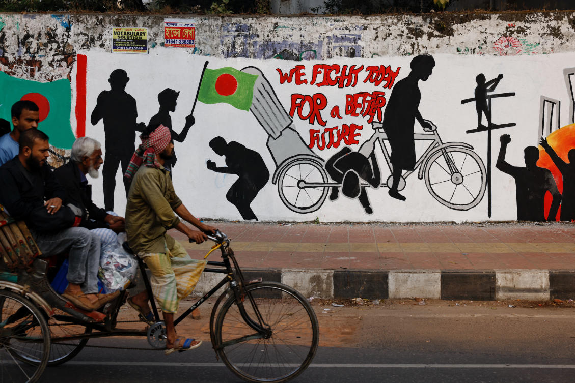 Commuters on a rickshaw pass by a graffiti illustrating Student Movement of 2024, in Dhaka, Bangladesh, January 1, 2025. (REUTERS)