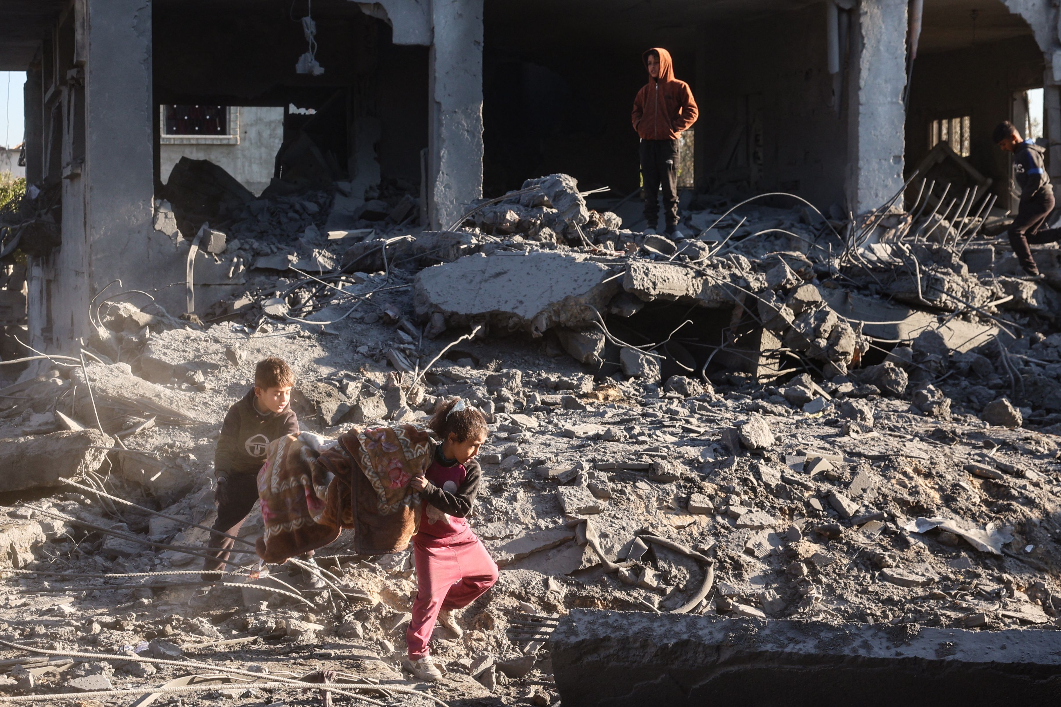 Palestinian children salvage a blanket amid the destruction in the aftermath of an Israeli strike in the al-Maghazi refugee camp in the central Gaza Strip on January 3, 2025, as the war between Israel and the Hamas movement continues. (AFP)
