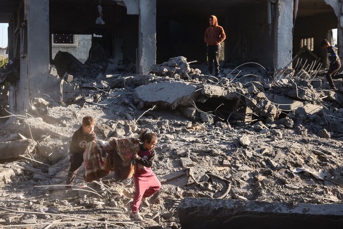 Palestinian children salvage a blanket amid the destruction in the aftermath of an Israeli strike in the Al-Maghazi refugee camp in the central Gaza Strip on January 3, 2025, as the war between Israel and the Hamas movement continues. (AFP)