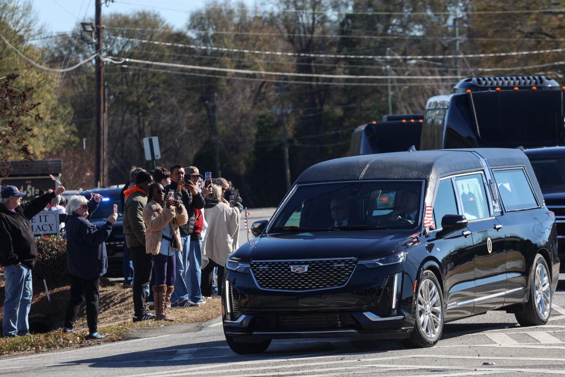 Mourners gather to pay their respects as the hearse containing the casket of former US President Jimmy Carter passes through Byron, Georgia, on Saturday. (AFP)