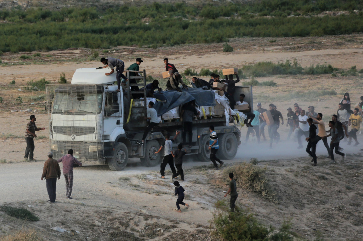 Palestinians rush trucks transporting international humanitarian aid from the US-built Trident Pier near Nuseirat in the central Gaza Strip on May 18, 2024, amid the ongoing conflict between Israel and the militant group Hamas. (AFP)