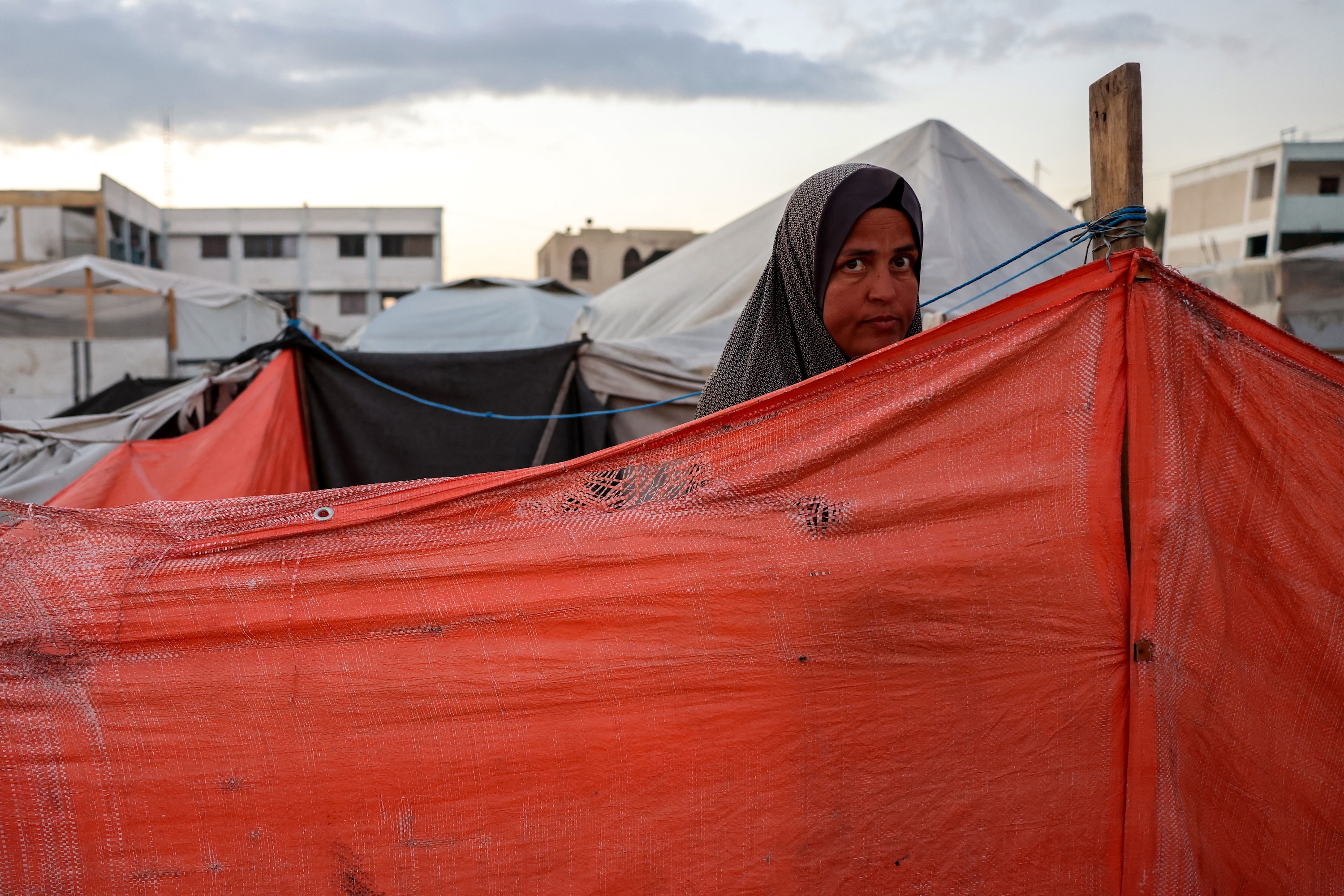 A woman looks on from behind a shelter at a camp for displaced Palestinians in Khan Yunis, in the southern Gaza Strip on Dec. 29, 2024 (AFP)