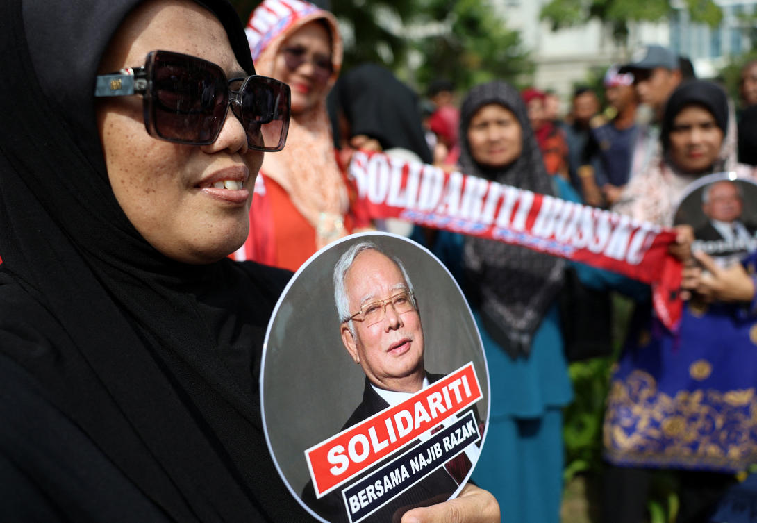 A supporter of former Malaysian Prime Minister Najib Razak holds a hand fan bearing his image outside the Court of Appeal, where his case is being heard in Putrajaya, Malaysia, January 6, 2025. (REUTERS)