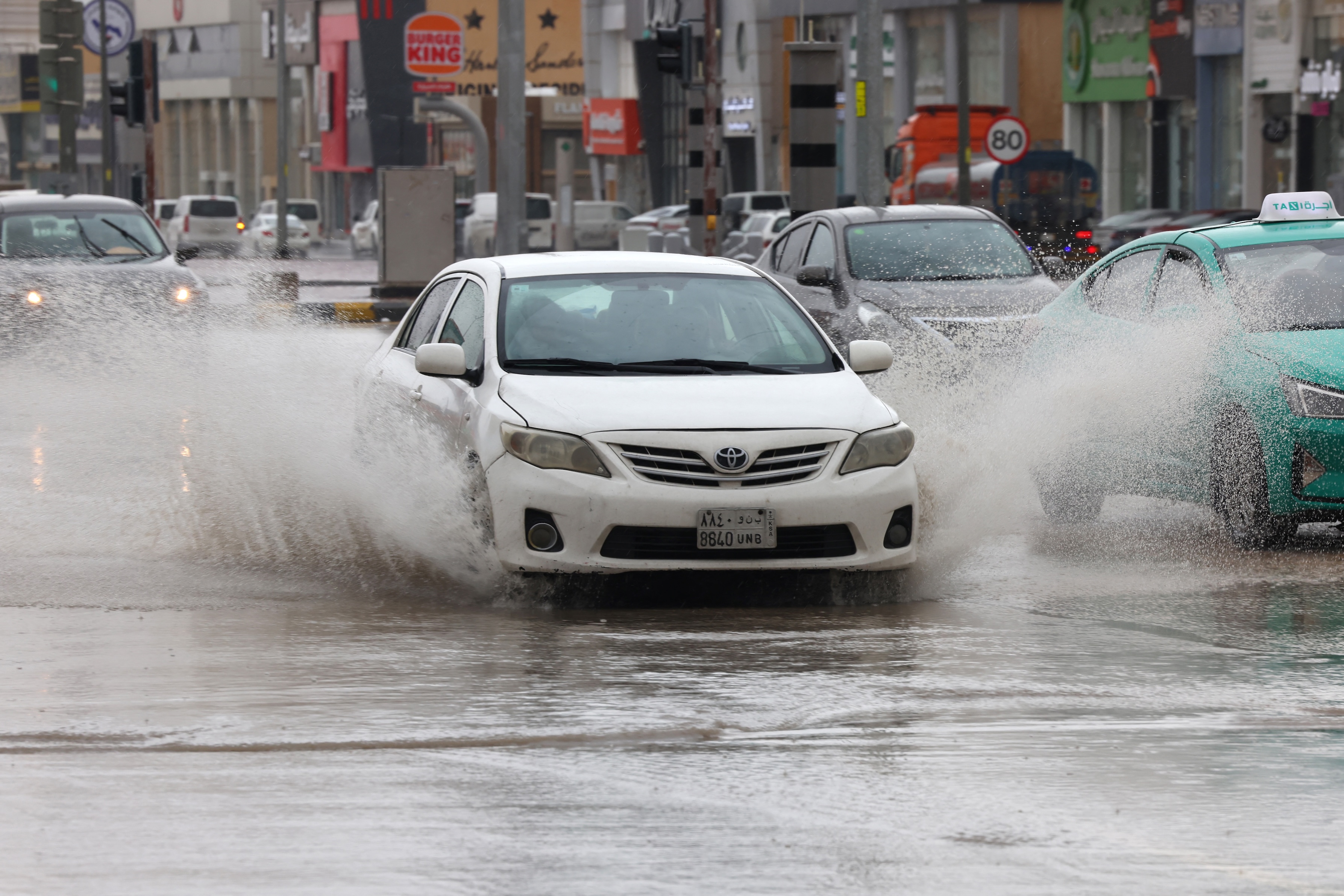 Cars drive through standing water in the Saudi capital, Riyadh, following strong winds and heavy rain, May 2024 (AFP)