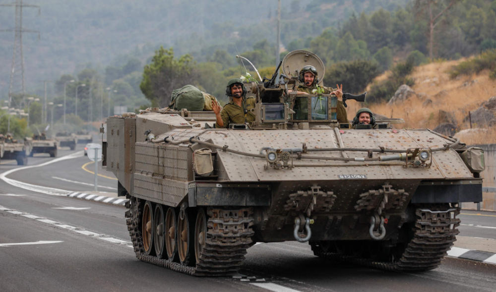 Israeli soldiers gesture in an armoured vehicle as they drive along a street near the northern town of Kiryat Shmona. (AFP/File)