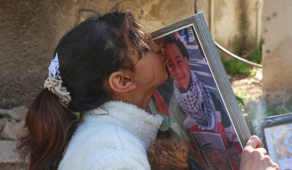 Batoul Ali Bsharat, 10, sister of Reda, 8, who was killed alongside his two cousins a day earlier in an Israeli airstrike, kisses his portrait set up in memoriam at the site of the strike in their town of Tammun in the occupied West Bank on January 9, 2025. (AFP)