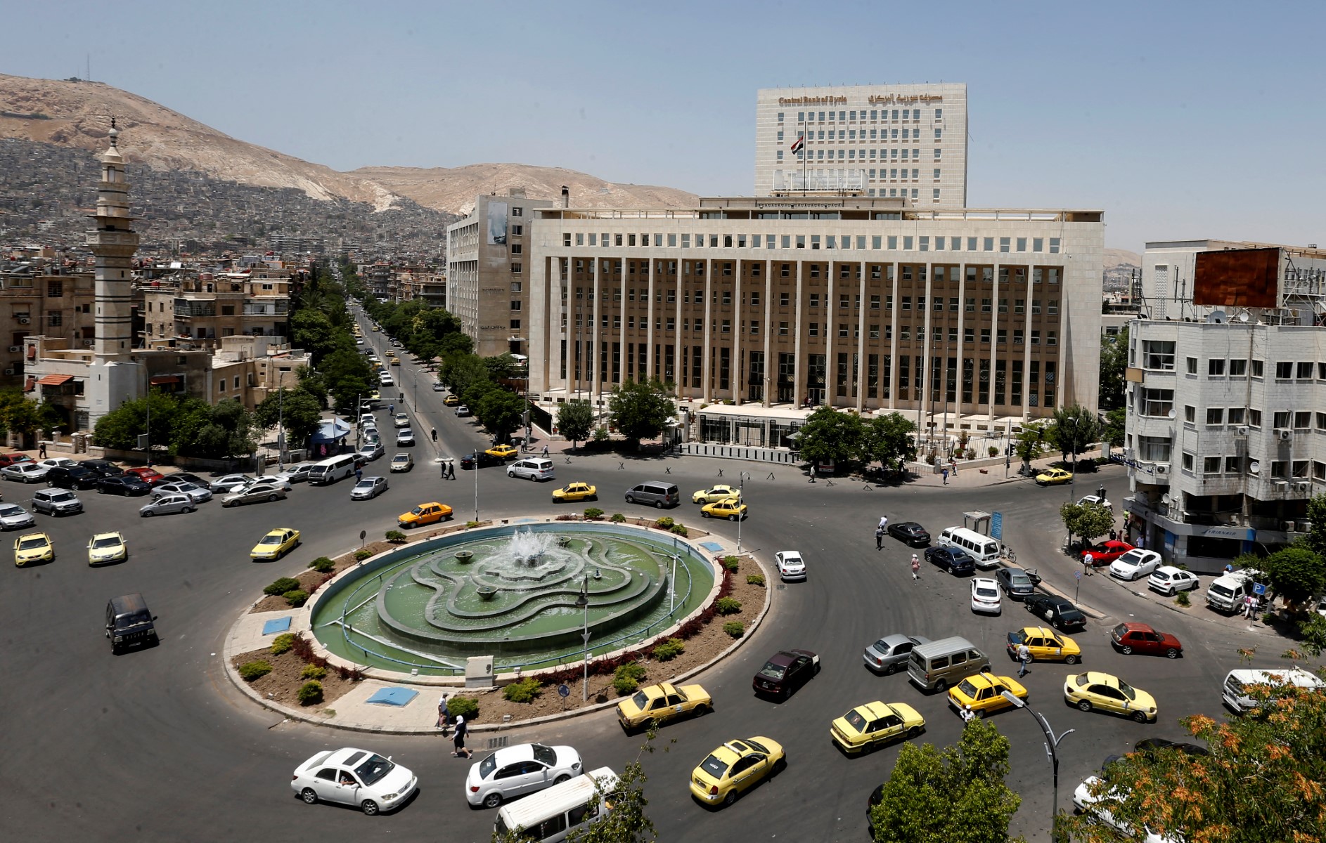 Vehicles drive along the roundabout past the Central bank of Syria in the capital Damascus' Sabaa Bahrat Square on June 17, 2020. (AFP)