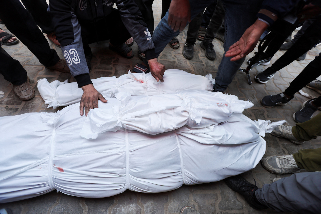 People stand next to the bodies of Palestinians killed in Israeli strikes at Al-Aqsa Martyrs Hospital, in Deir Al-Balah in the Gaza Strip, January 14, 2025. (Reuters)