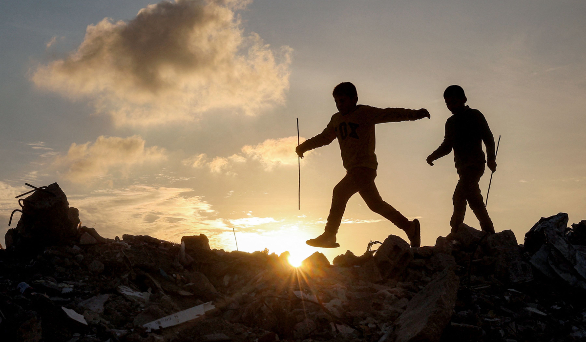 Boys walk atop a mound of rubble at a camp for people displaced by conflict in Bureij in the central Gaza Strip on January 17, 2025 following the announcement of a truce amid the ongoing war between Israel and Hamas. (AFP)