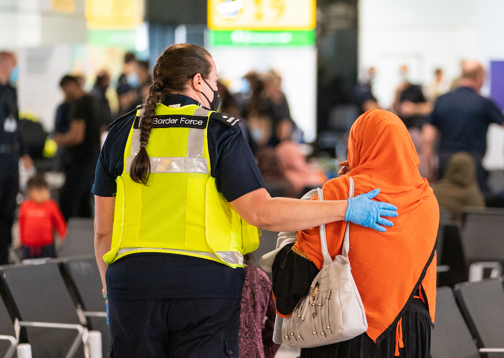A member of Border Force staff assists an Afghan refugee on her arrival on an evacuation flight from Afghanistan at Heathrow Airport, London on Aug. 26, 2021. (AFP file photo)